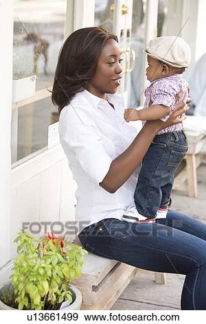 Stock Photo - Portrait of smiling woman holding son (12-17 months). Fotosearch