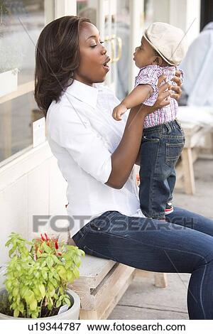Stock Photo - Portrait of smiling woman holding son (12-17 months). Fotosearch