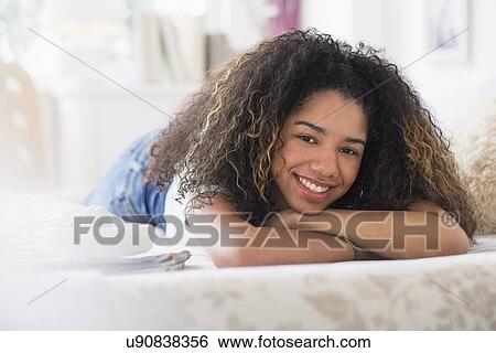 Stock Photograph - Portrait of teenage girl (16-17) lying on bed. Fotosearch
