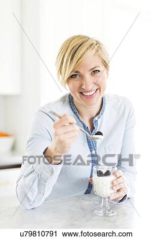Portrait of woman eating yogurt with blackberries View Large Photo Image Stock Image - Portrait of woman eating yogurt with blackberries. Fotosearch