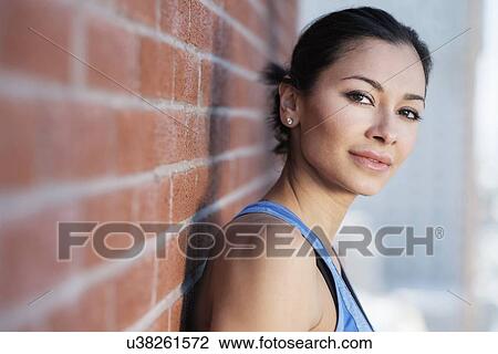 Portrait of young woman by brick wall View Large Photo Image Stock Image - Portrait of young woman by brick wall. Fotosearch