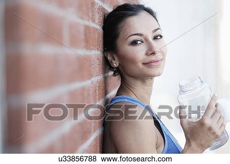 Portrait of young woman by brick wall View Large Photo Image Stock Photo - Portrait of young woman by brick wall. Fotosearch