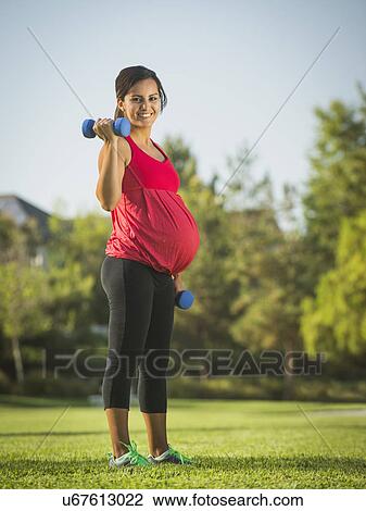 Stock Image - Pregnant woman exercising outdoors. Fotosearch