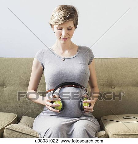Pregnant woman holding headphones on abdomen View Large Photo Image Stock Image - Pregnant woman holding headphones on abdomen. Fotosearch