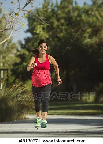 Stock Image - Pregnant woman running outdoors. Fotosearch