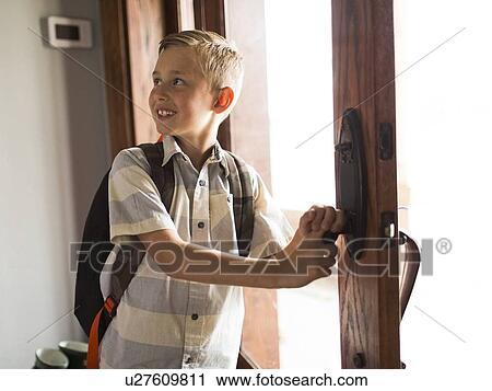 Stock Image - Smiling boy (6-7) leaving for school. Fotosearch