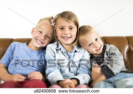 Smiling children (2-3, 4-5) sitting on sofa View Large Photo Image Stock Photo - Smiling children (2-3, 4-5) sitting on sofa . Fotosearch