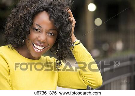 Stock Photograph - Smiling woman with hand in hair. Fotosearch