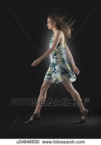 Studio shot of young woman walking View Large Photo Image Stock Image - Studio shot of young woman walking. Fotosearch
