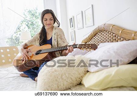 Stock Image - Teenage girl (14-15) playing guitar. Fotosearch