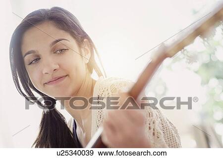 Stock Photo - Teenage girl (14-15) playing guitar. Fotosearch