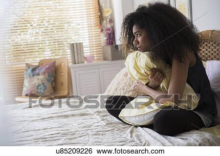 Teenage girl (14-15) sitting on bed, embracing pillow View Large Photo Image Stock Photograph - Teenage girl (14-15) sitting on bed, embracing pillow. Fotosearch