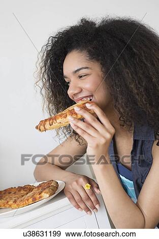 Stock Photo - Teenage girl (16-17) eating pizza. Fotosearch