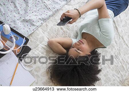 Teenage girl (16-17) texting in bedroom View Large Photo Image Stock Image - Teenage girl (16-17) texting in bedroom. Fotosearch