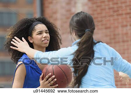 Stock Image - Teenage girls (14-15, 16-17) playing basketball. Fotosearch