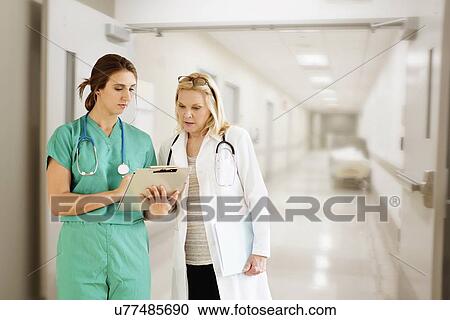 Stock Image - Two female doctors looking at medical documents. Fotosearch