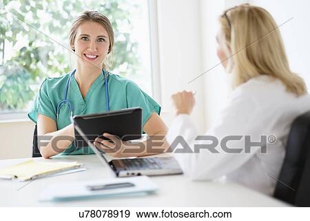 Two female doctors talking in office View Large Photo Image Stock Photo - Two female doctors talking in office. Fotosearch
