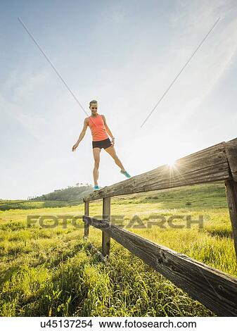 Woman balancing on wooden fence View Large Photo Image Picture - Woman balancing on wooden fence. Fotosearch