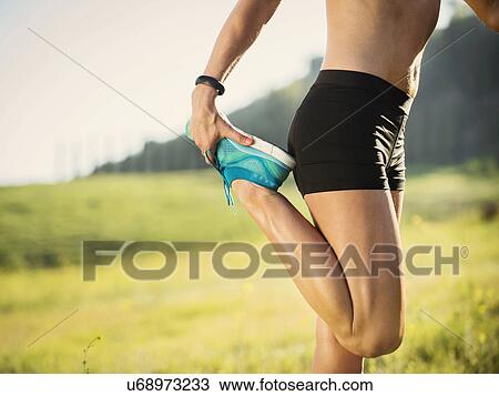 Stock Image - Woman exercising in field. Fotosearch