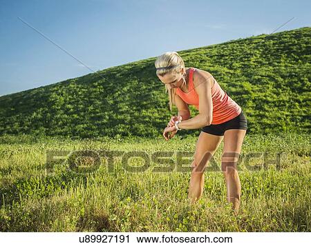 Stock Image - Woman exercising in field. Fotosearch