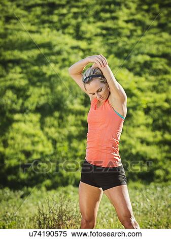 Stock Photography - Woman exercising in field. Fotosearch