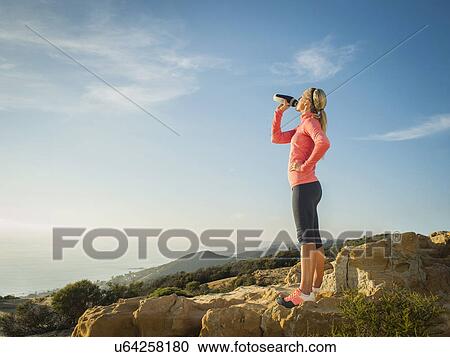 Stock Image - Woman in sportswear drinking water. Fotosearch
