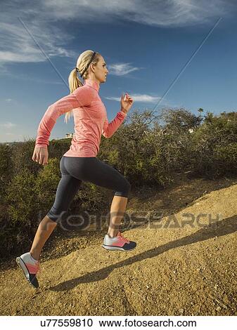 Stock Image - Woman running in mountains. Fotosearch