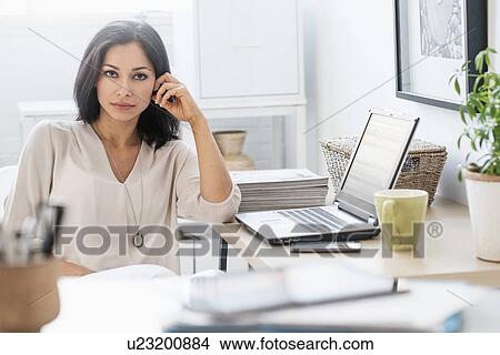 Picture - Woman sitting at desk with laptop. Fotosearch