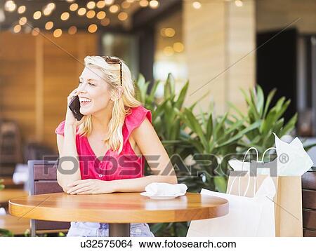Picture - Woman talking on phone in cafe. Fotosearch