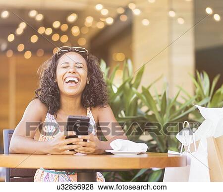 Stock Photo - Woman using phone in cafe. Fotosearch