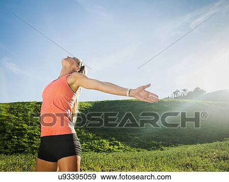 Stock Photo - Woman with outstretched arms in field. Fotosearch