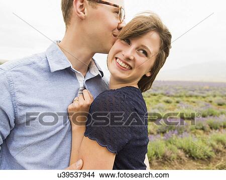 Picture - Young couple embracing with field on background. Fotosearch