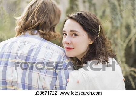 Stock Image - Young smiling woman next to boyfriend. Fotosearch