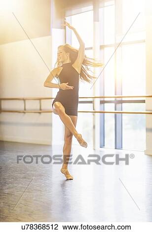 Stock Image - Young woman dancing in dance studio. Fotosearch
