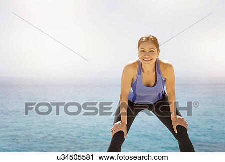 Stock Image - Young woman exercising by sea. Fotosearch