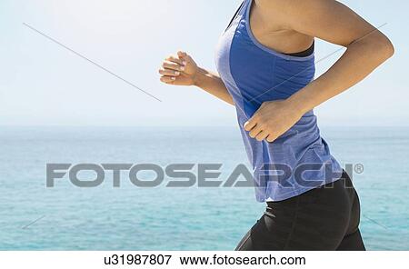 Stock Photo - Young woman exercising by sea. Fotosearch