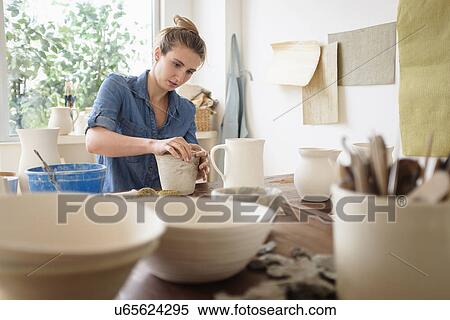Stock Photography - Young woman making pottery in studio. Fotosearch