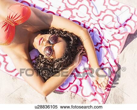 Stock Photography - Young woman sunbathing on beach. Fotosearch