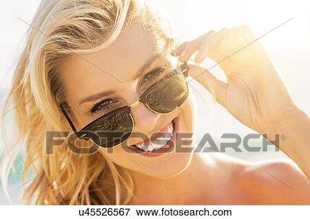 Stock Photo - Young woman wearing sunglasses. Fotosearch