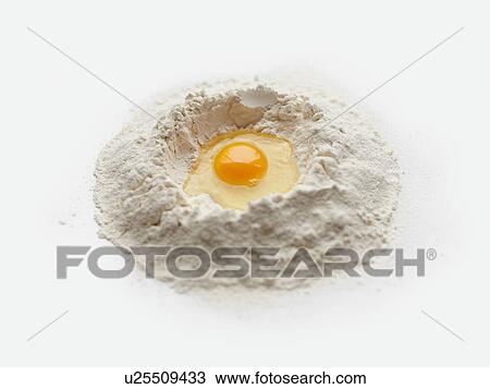 Stock Image - Baking preparation with raw egg in center of flour stack. Fotosearch