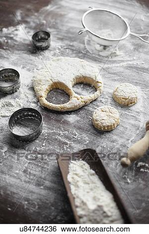 Stock Photograph - Baking preparation with scone dough and pastry cutters on table. Fotosearch