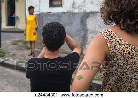 Stock Image - Behind the scenes of an urban fashion shoot with female model and male photographer. Fotosearch
