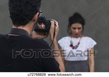 Stock Photo - Behind the scenes of an urban fashion shoot with female model and male photographer. Fotosearch