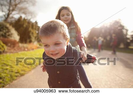 Boy and sister playing in park View Large Photo Image Stock Image - Boy and sister playing in park. Fotosearch