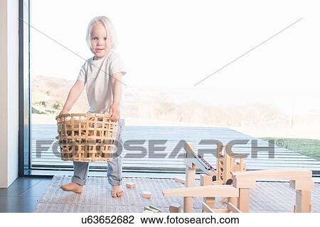 Stock Image - Boy carrying basket of wooden blocks. Fotosearch
