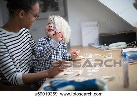 Boy holding scissors looking at his mother View Large Photo Image Stock Photo - Boy holding scissors looking at his mother. Fotosearch