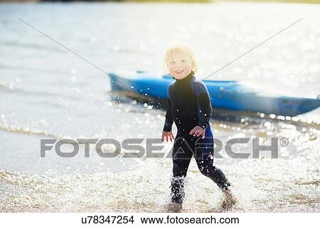 Picture - Boy in water with canoe in background. Fotosearch