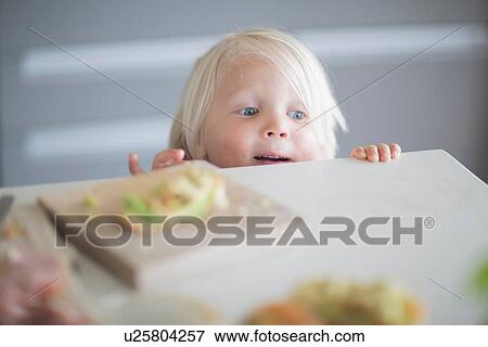 Stock Photo - Boy peeking over kitchen counter. Fotosearch