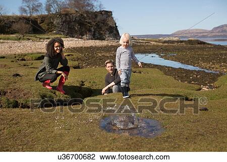 Stock Image - Boy throwing rock into puddle, Isle of Skye, Hebrides, Scotland. Fotosearch
