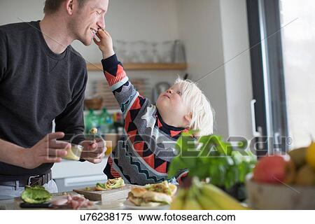 Stock Photography - Boy touching father's face in kitchen. Fotosearch